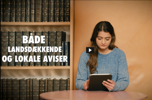 Ung kvinde studerer aviser på tablet